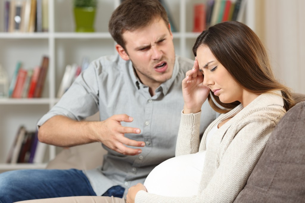 A man talking angrily to a pregnant woman